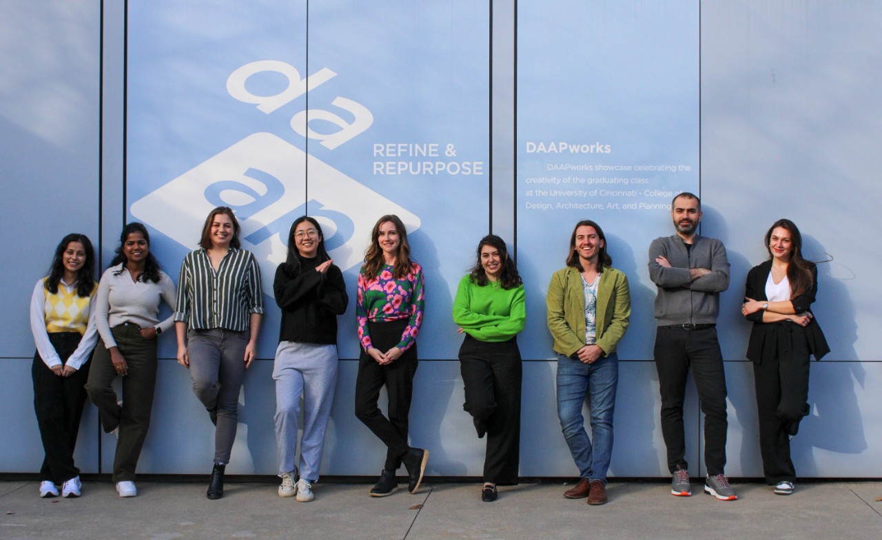 MLA Class of 2024 group photo in front of the DAAPworks branding outside the fifth floor of DAAP.