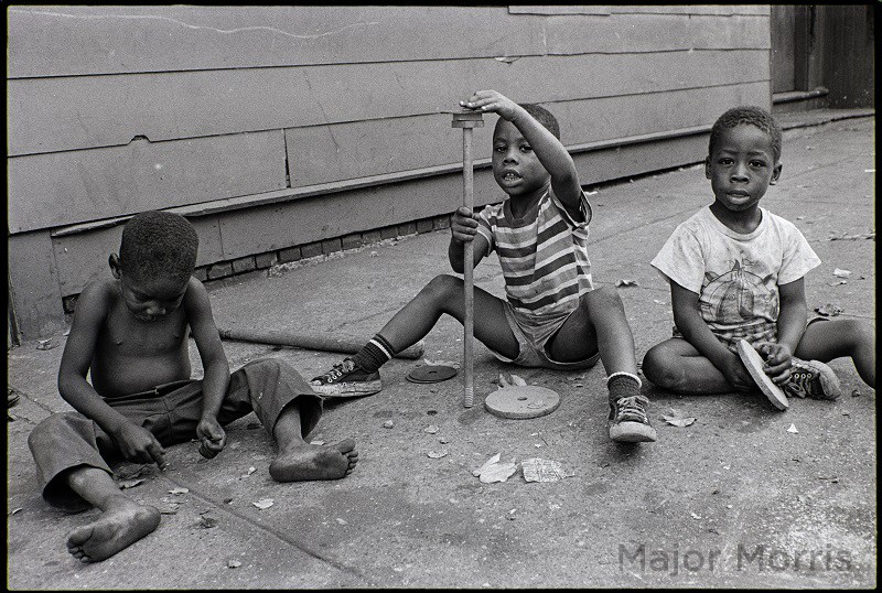 Three children playing on sidewalk