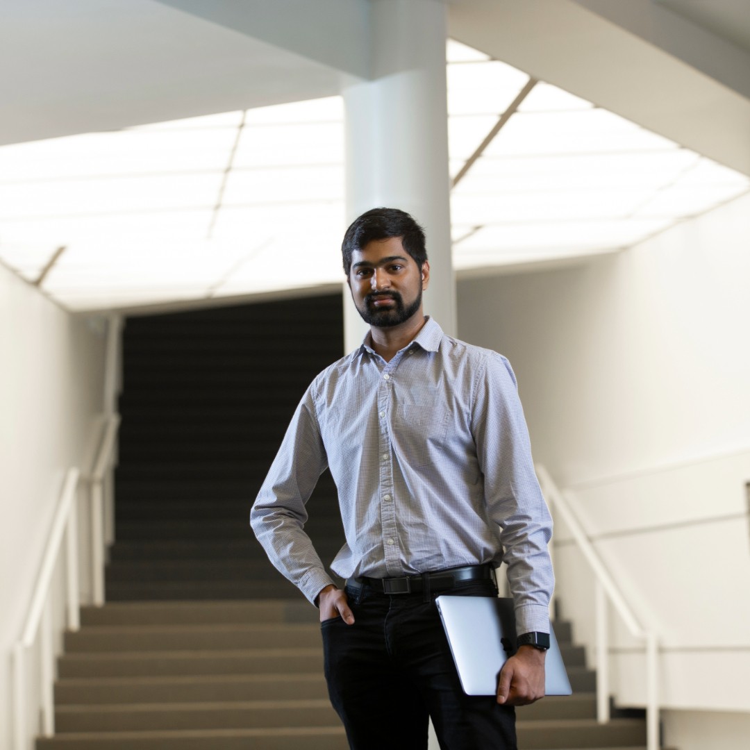 Student Advisor standing on the grand staircase holding a laptop.