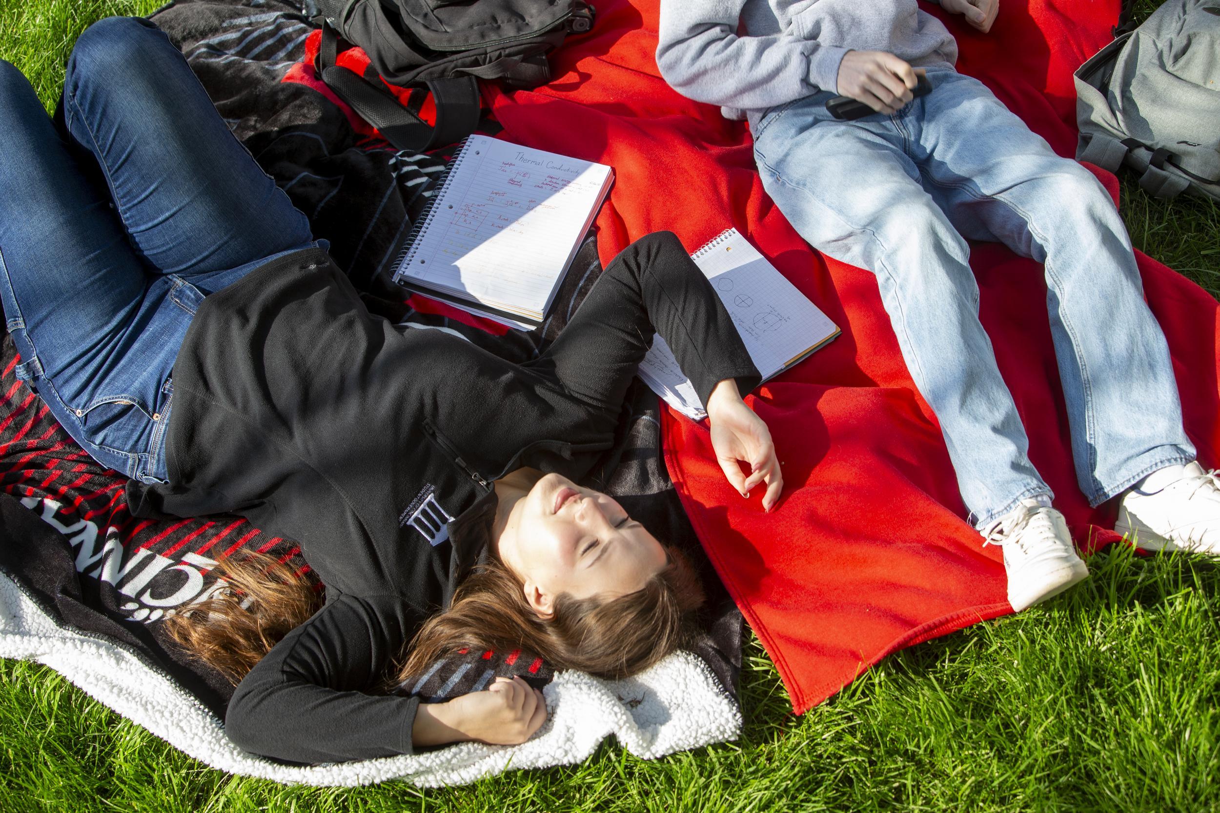 UC students relaxing on campus green space.